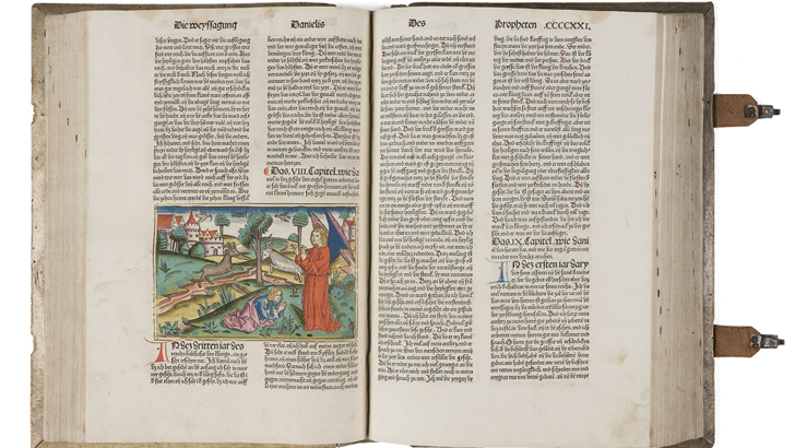 Medieval bible open at pages showing a colour illustration and printed text in Latin