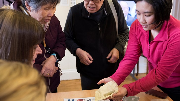 Group of adults looking at objects from a handling box