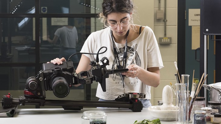 A woman looks down at camera equipment