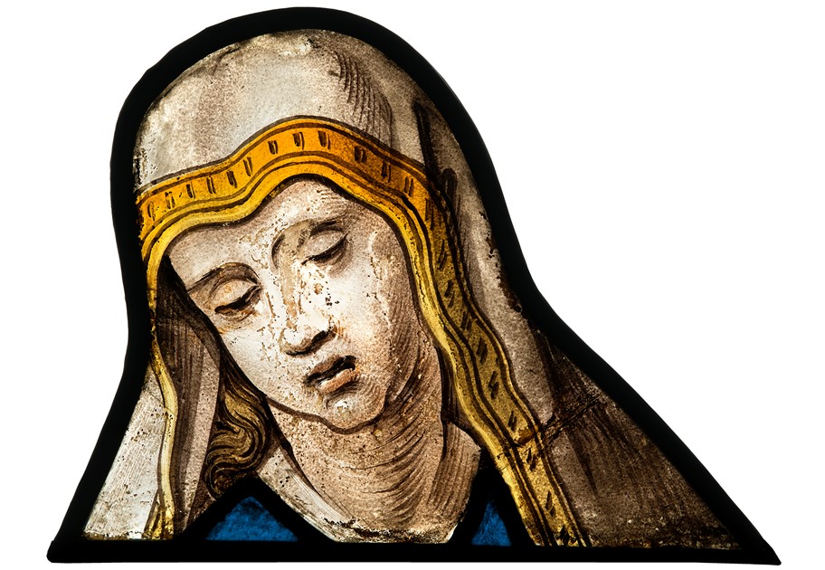 Image is a photograph of coloured, stained and painted glass. It is a lead fragment of the Virgin Mary in mourning.