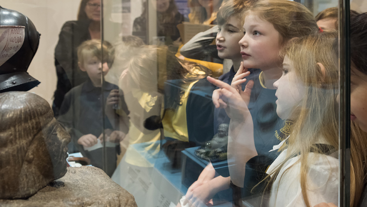 Large group of children looking at an object in a glass cabinet