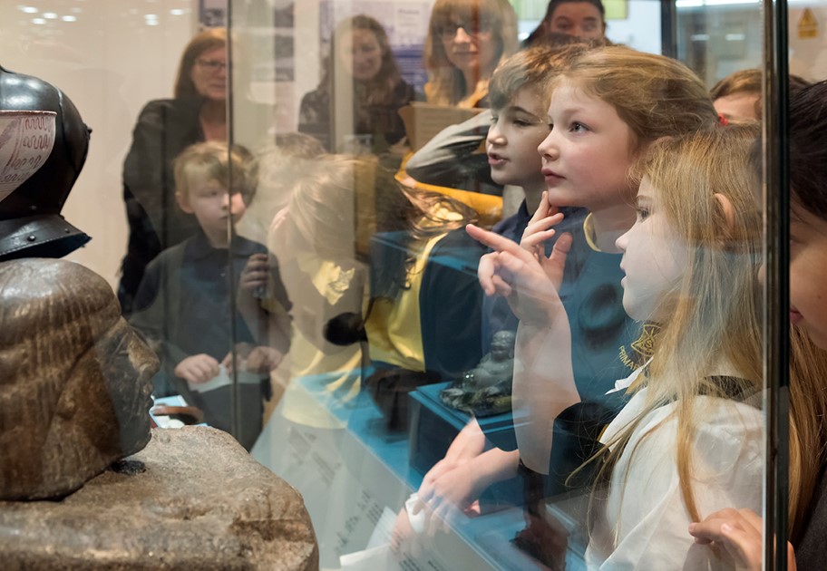 Large group of children looking at an object in a glass cabinet