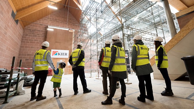 A group in protective clothing and helmets visit a building site