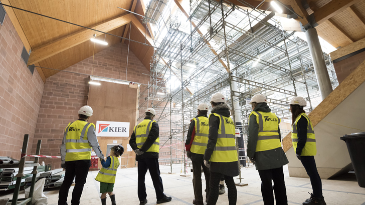 A group in protective clothing and helmets visit a building site