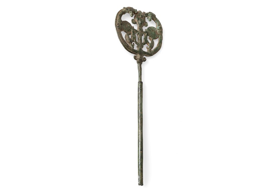 The image shows a photograph of a bronze hairpin